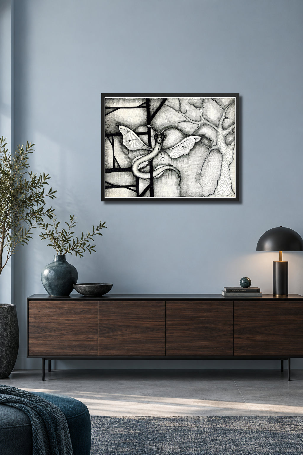 Dragonakee by MatiArtBox printable wall art mockup showing a framed black-and-white hand-drawn artwork above a dark gray sofa in a modernlight-blue-gray living room. 